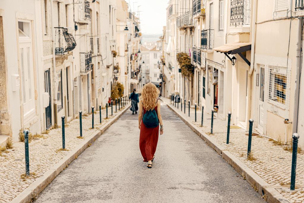 young-female-red-dress-walking-through-road-surrounded-by-buildings-sunlight.jpg